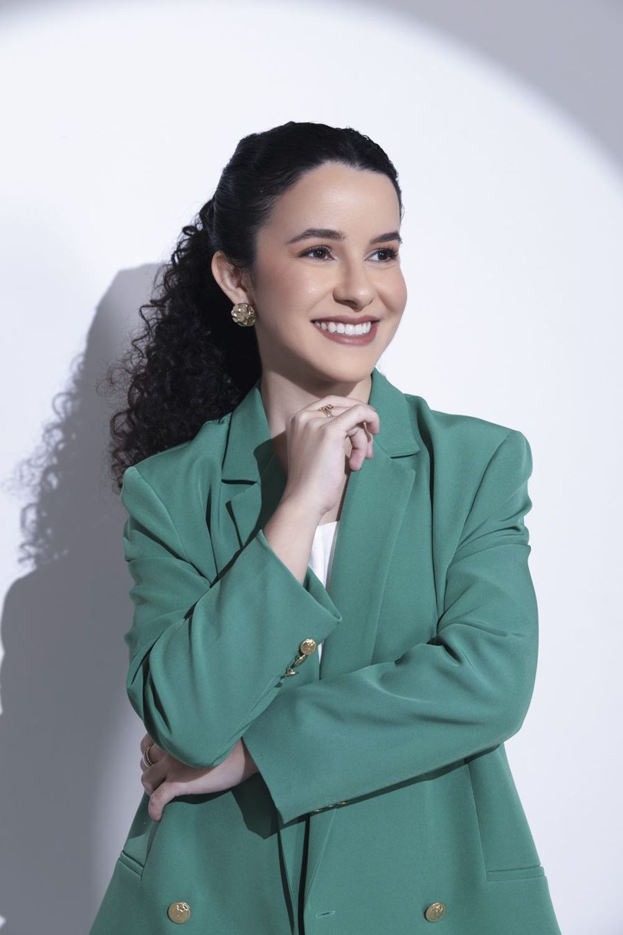 Retrato da Dra. Larissa Quariguasi, sorrindo, com a mão próxima ao queixo